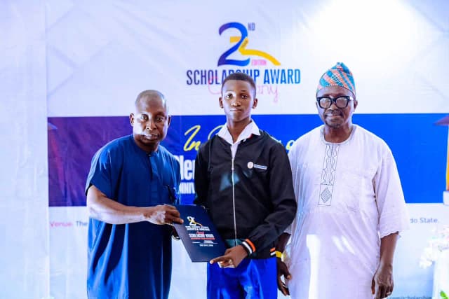 Empowering future leaders: A male student proudly accepts his scholarship certificate on stage from local administrative dignitaries.