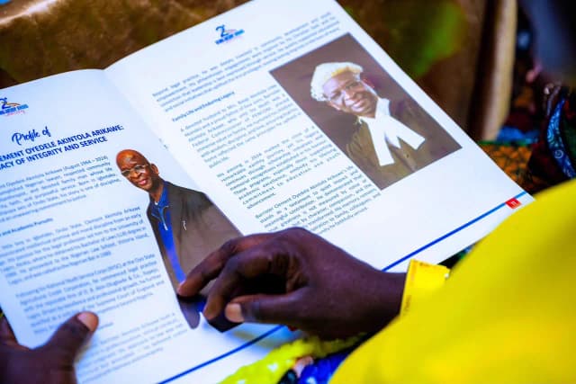 Learning from the past: A guest reads the biography of late Barr. Clement Oyedele Akintola Arikawe in the program booklet.