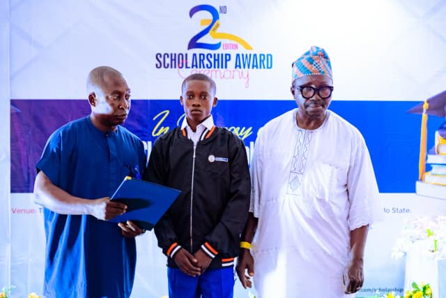 Merit recognition: A male student receives his scholarship folder on stage.