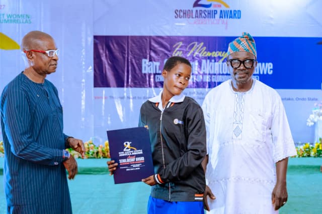 A proud moment: A female student stands on stage holding her scholarship award.