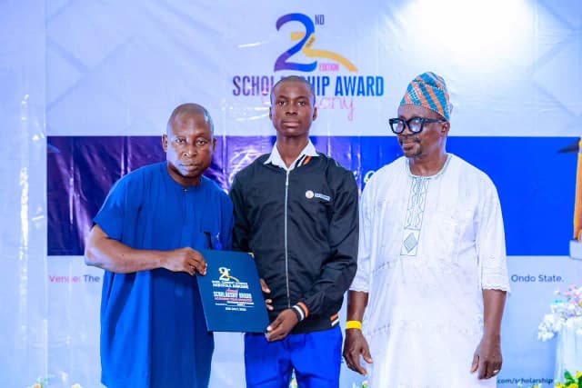 Recognizing potential: A male scholar is presented with his merit-based award folder.