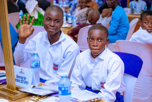 Scholars spotlight: Two SSS2 students seated at the reserved awardees table wave cheerfully to the camera.