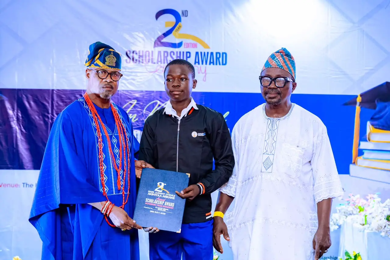 Dignitaries present a merit scholarship to a top-performing student during the 2026 memorial award ceremony.