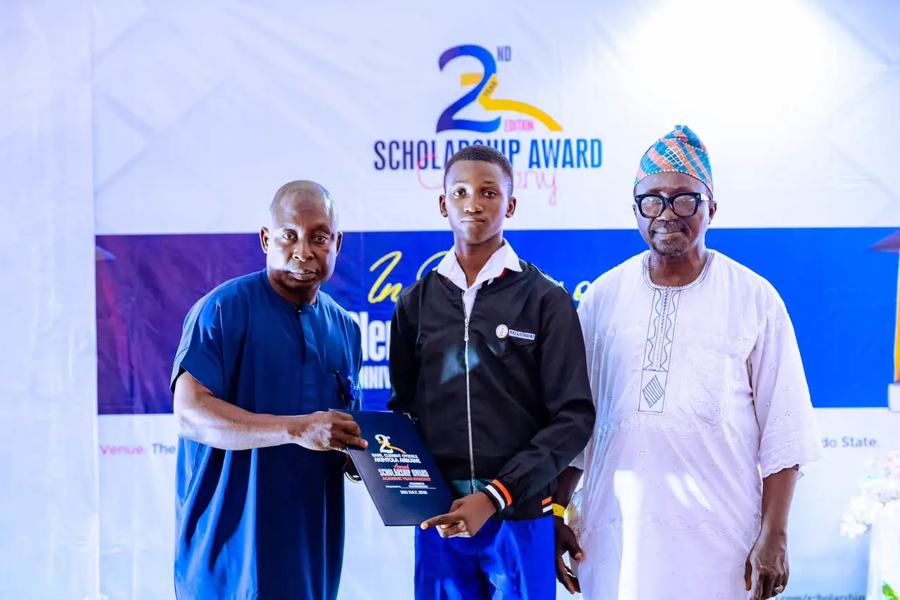 Empowering future leaders: A male student proudly accepts his scholarship certificate on stage from local administrative dignitaries.